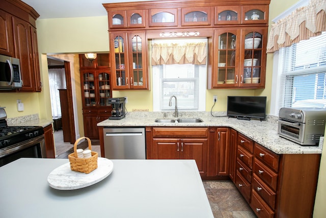 kitchen with stainless steel appliances, light stone counters, and sink