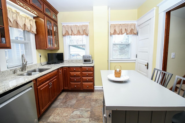 kitchen featuring dishwasher, light stone countertops, and sink