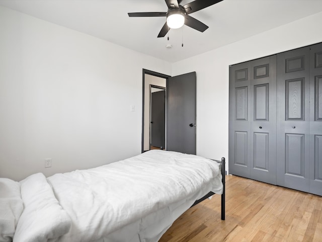 bedroom with a closet, light hardwood / wood-style floors, and ceiling fan