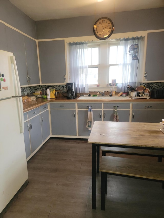 kitchen with white fridge, sink, backsplash, and dark wood-type flooring