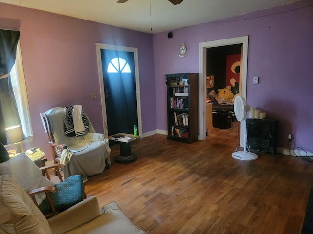 living room featuring a wood stove, ceiling fan, and hardwood / wood-style flooring