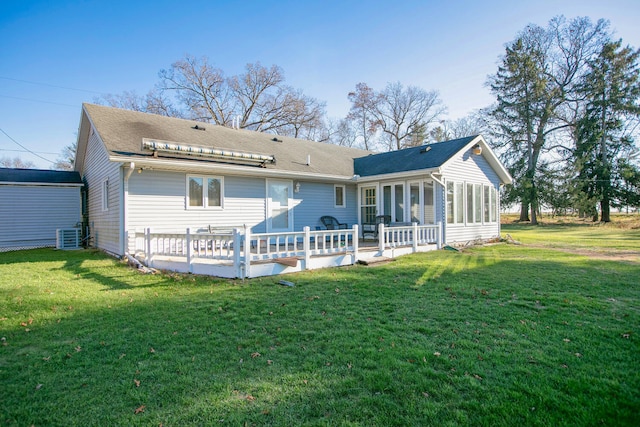 rear view of house featuring a lawn, a sunroom, and a deck