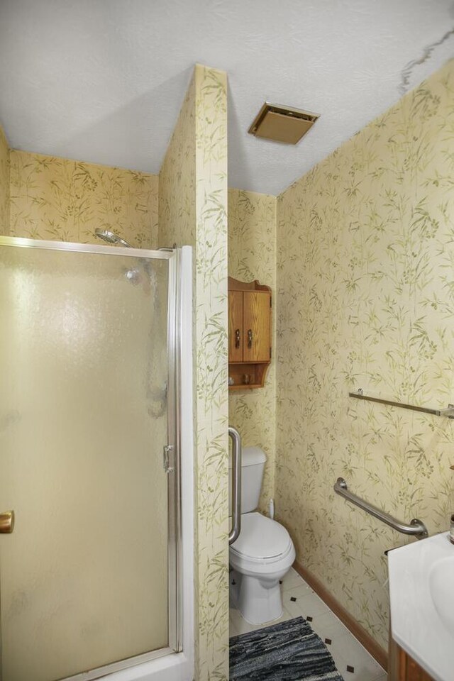 bathroom featuring tile patterned floors, vanity, a shower with shower door, and toilet