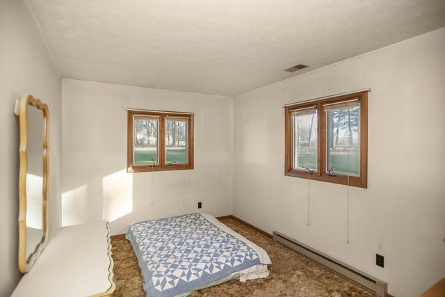 carpeted bedroom with a textured ceiling and baseboard heating