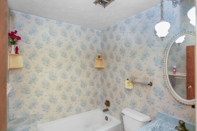 bathroom with a bath, a textured ceiling, and toilet