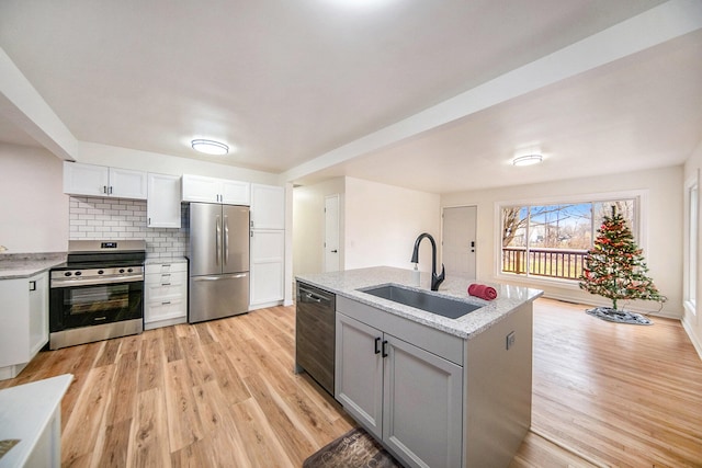 kitchen with sink, white cabinetry, light hardwood / wood-style flooring, appliances with stainless steel finishes, and decorative backsplash