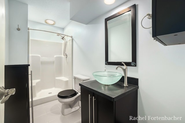 bathroom with tile patterned flooring, vanity, toilet, and walk in shower