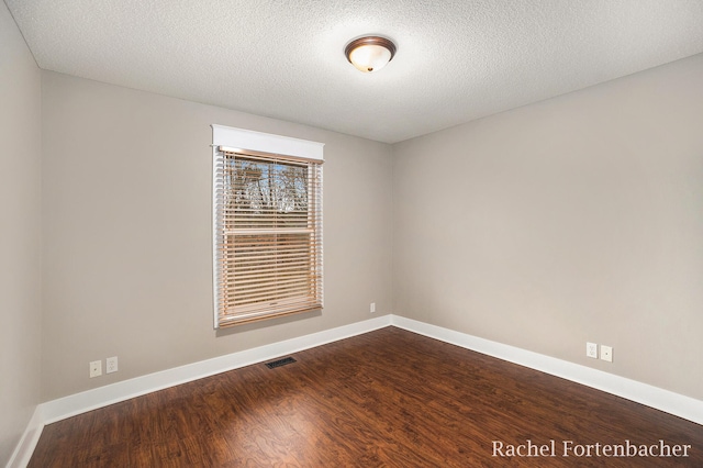 empty room with wood-type flooring and a textured ceiling