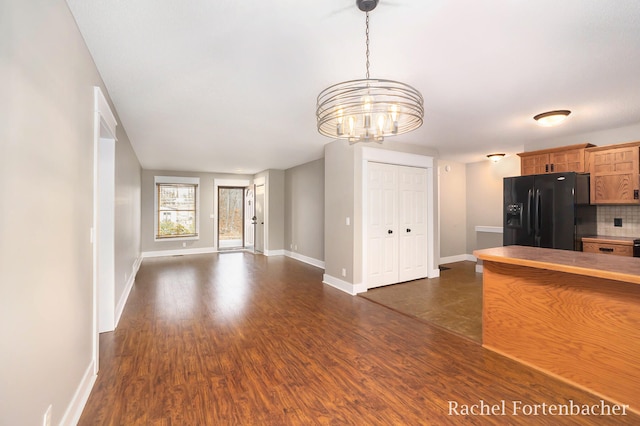 kitchen featuring decorative backsplash, dark hardwood / wood-style flooring, black refrigerator with ice dispenser, an inviting chandelier, and hanging light fixtures