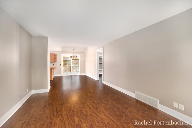 unfurnished living room with dark hardwood / wood-style flooring and a chandelier