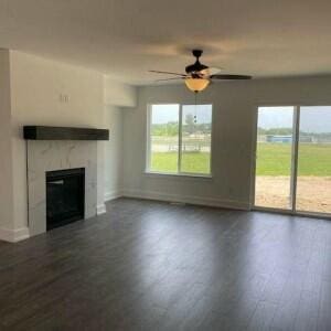 unfurnished living room featuring dark hardwood / wood-style floors, ceiling fan, and a tiled fireplace