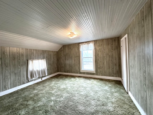 additional living space featuring dark colored carpet, wood walls, lofted ceiling, and wooden ceiling