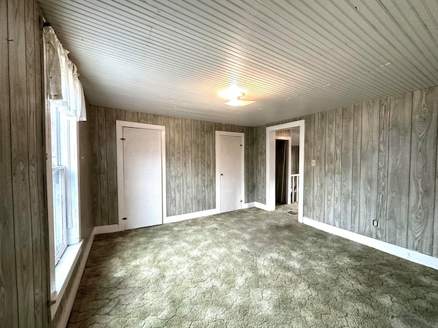 unfurnished bedroom with dark carpet and wooden walls