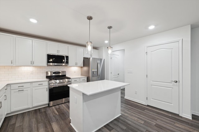 kitchen with white cabinets, dark hardwood / wood-style floors, hanging light fixtures, and appliances with stainless steel finishes