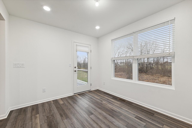 unfurnished room featuring dark wood-type flooring and a healthy amount of sunlight