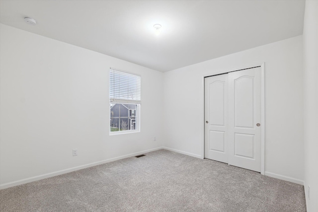 unfurnished bedroom with light colored carpet and a closet