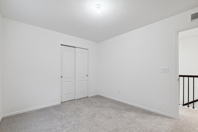 unfurnished bedroom featuring light carpet and a closet