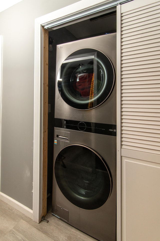 laundry room featuring stacked washer / drying machine and light wood-type flooring