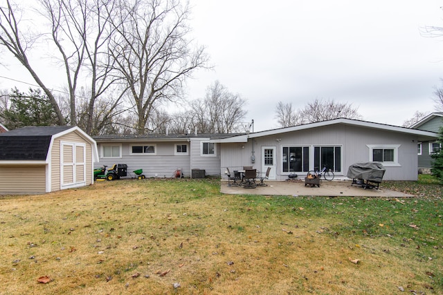 rear view of property with a lawn, cooling unit, a patio, and a storage unit