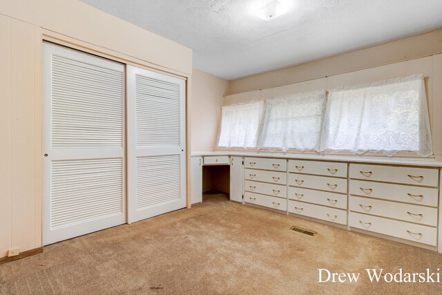 unfurnished bedroom with light carpet, a closet, and a textured ceiling