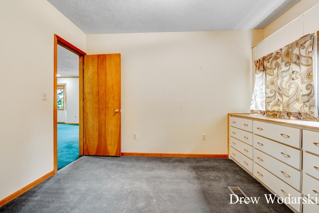 unfurnished bedroom featuring dark colored carpet and a textured ceiling