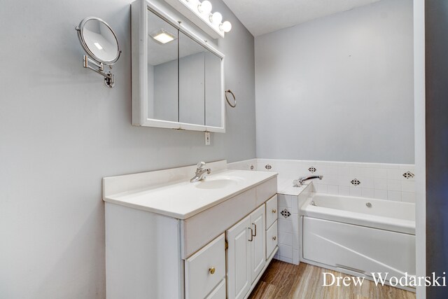 bathroom with a washtub, vanity, and hardwood / wood-style flooring