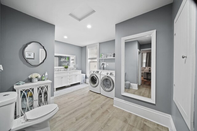 washroom with light hardwood / wood-style floors, separate washer and dryer, and sink