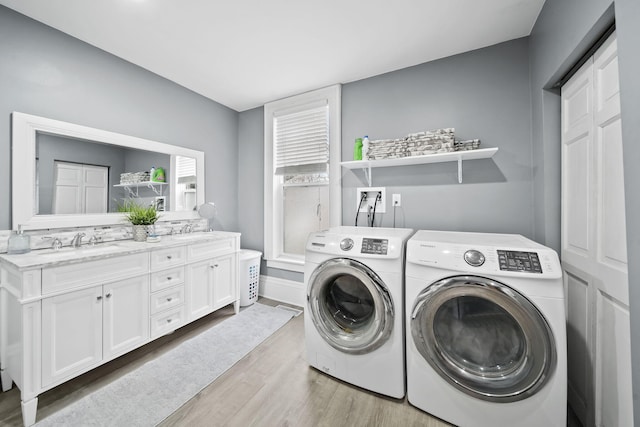 clothes washing area featuring independent washer and dryer, light hardwood / wood-style floors, and sink