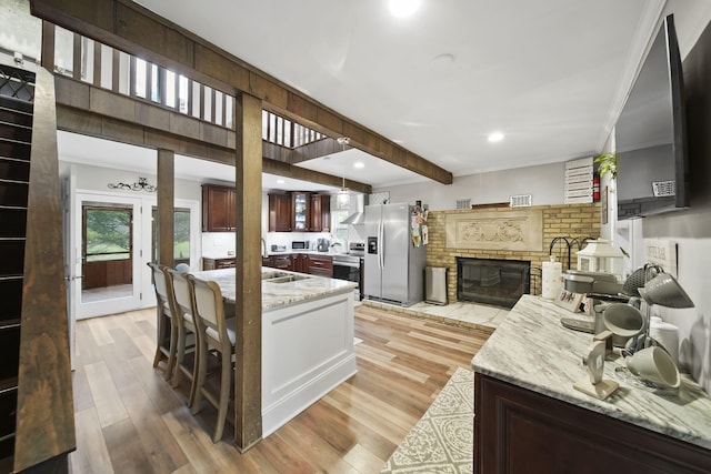 kitchen with light stone countertops, stainless steel appliances, and light hardwood / wood-style flooring