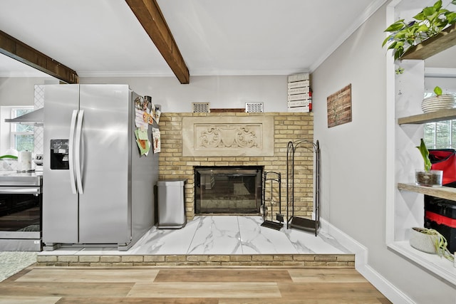 interior space featuring beam ceiling, a brick fireplace, crown molding, wood-type flooring, and appliances with stainless steel finishes