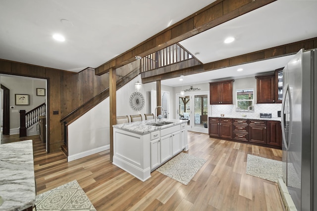 kitchen with white cabinets, sink, light wood-type flooring, a kitchen island, and stainless steel refrigerator