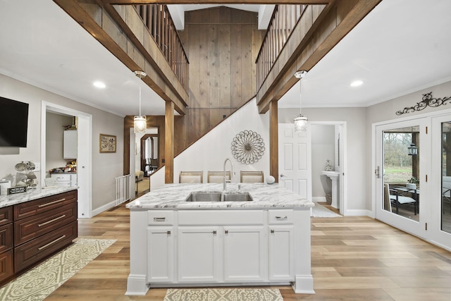 kitchen featuring pendant lighting, white cabinetry, light wood-type flooring, and sink