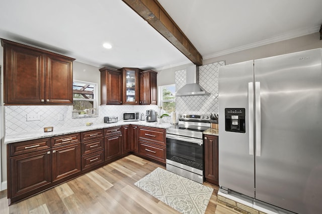 kitchen featuring wall chimney exhaust hood, a healthy amount of sunlight, appliances with stainless steel finishes, and tasteful backsplash