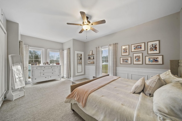 bedroom featuring ceiling fan, light carpet, and multiple windows