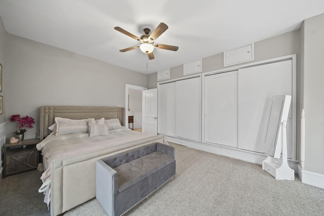 carpeted bedroom with ceiling fan and two closets