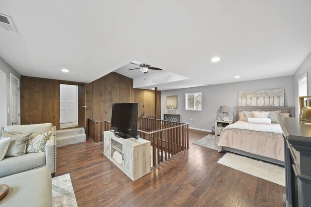 bedroom featuring dark hardwood / wood-style floors, ceiling fan, and wood walls