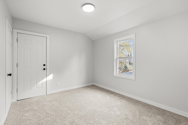 carpeted empty room featuring lofted ceiling