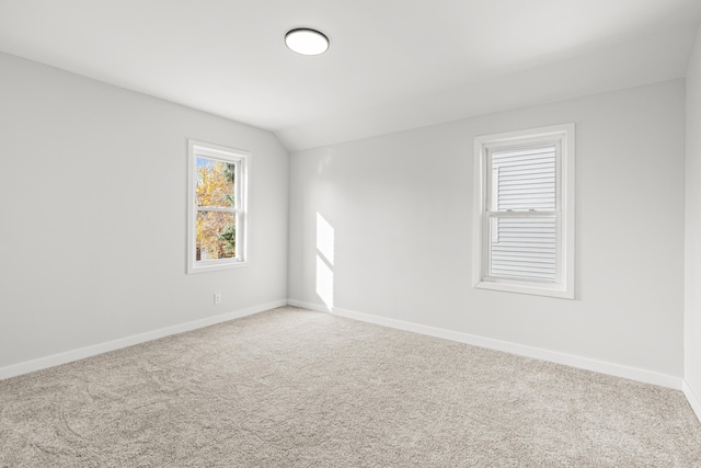 carpeted spare room with vaulted ceiling