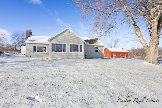 snow covered back of property with a chimney and fence