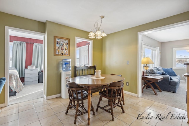 dining room with a chandelier, light tile patterned flooring, baseboards, and light carpet