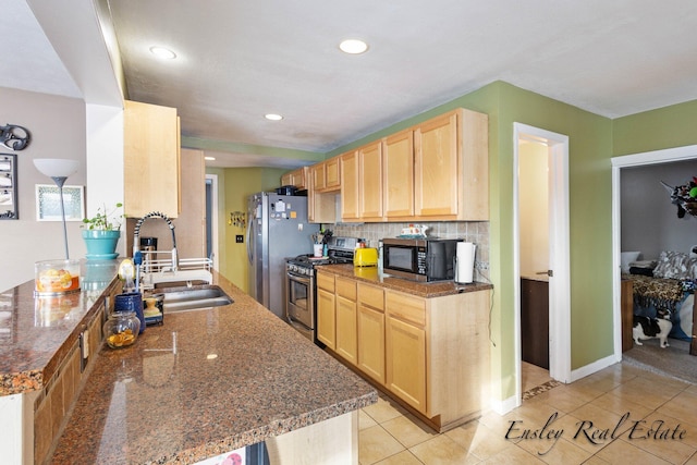 kitchen featuring a sink, decorative backsplash, light brown cabinetry, light tile patterned floors, and appliances with stainless steel finishes