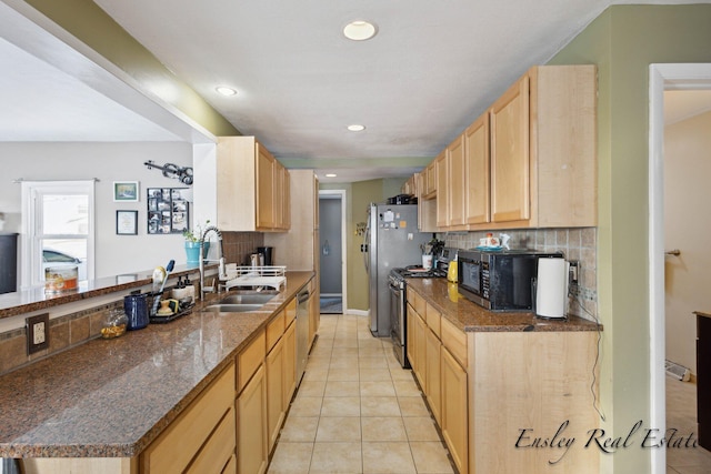 kitchen featuring a sink, light tile patterned flooring, backsplash, light brown cabinets, and appliances with stainless steel finishes
