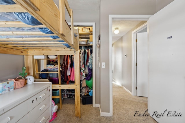 bedroom with baseboards, a closet, and light colored carpet