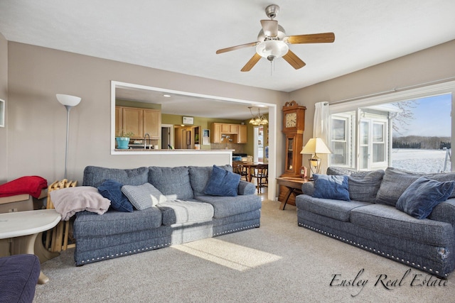 carpeted living room with ceiling fan with notable chandelier