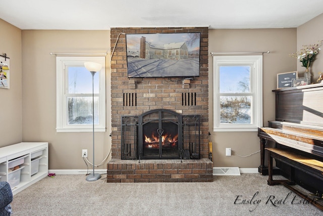 carpeted living area featuring a fireplace, a healthy amount of sunlight, and baseboards