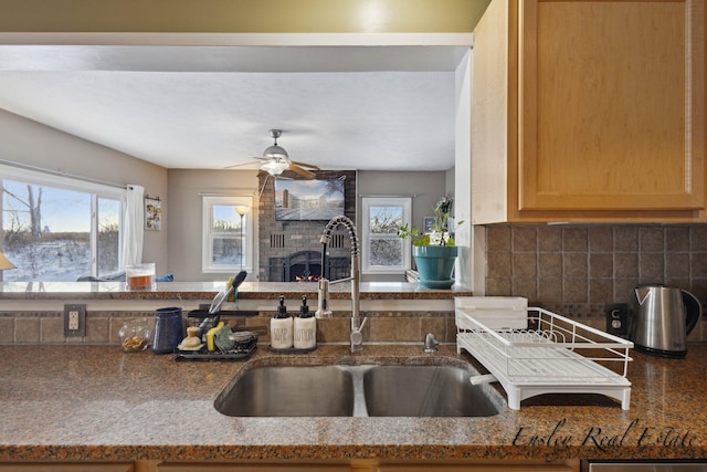 kitchen with backsplash, a brick fireplace, a wealth of natural light, and a sink