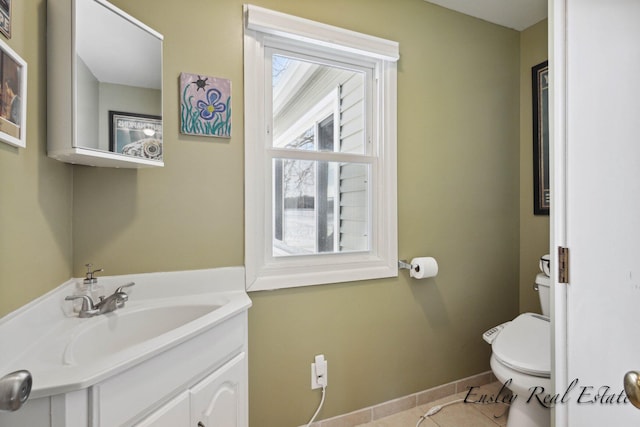 half bath with tile patterned floors, baseboards, vanity, and toilet