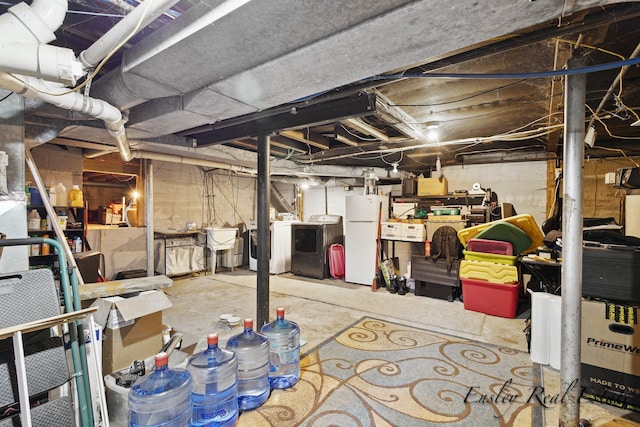 unfinished basement featuring separate washer and dryer, a sink, and freestanding refrigerator