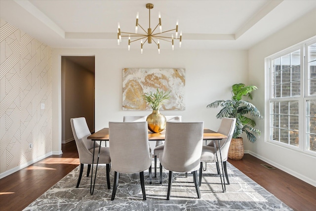 dining room featuring a tray ceiling, dark hardwood / wood-style floors, and a notable chandelier