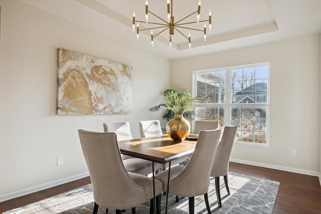 dining space featuring an inviting chandelier, dark hardwood / wood-style floors, and a raised ceiling